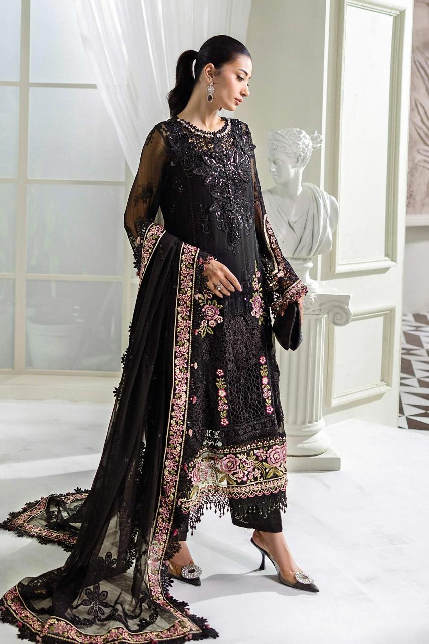 Woman wearing a black embroidered traditional outfit in a white room.